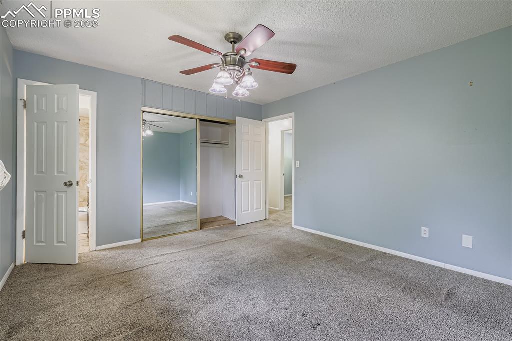Image 12 of 28: Unfurnished bedroom with carpet floors, a closet, a ceiling fan, a textured