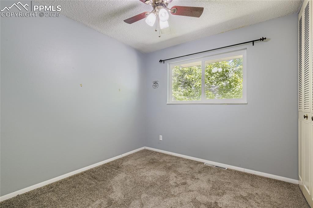 Image 15 of 28: Spare room with carpet, a textured ceiling, and ceiling fan