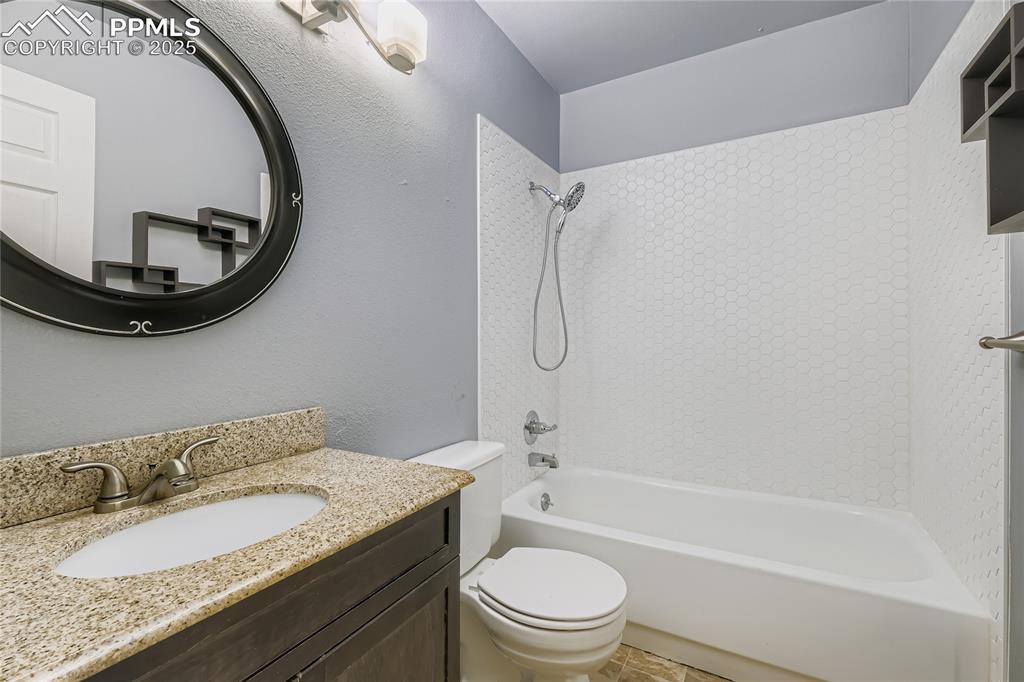 Image 17 of 28: Full bathroom featuring shower / bath combination, vanity, and a textured w