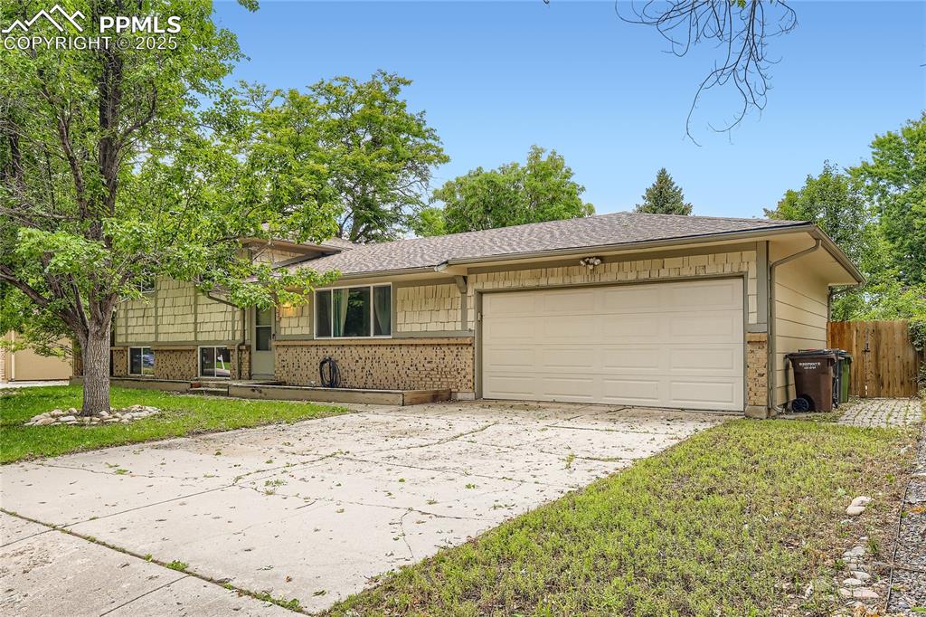 Image 2 of 28: Split level home with driveway, an attached garage, and a shingled roof