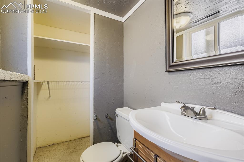 Image 21 of 28: Bathroom featuring a textured wall, a walk in closet, and vanity