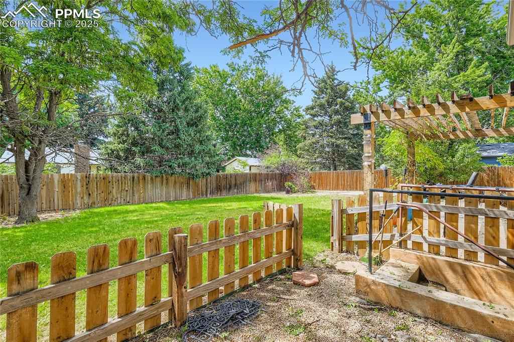 Image 28 of 28: Fenced backyard featuring a pergola