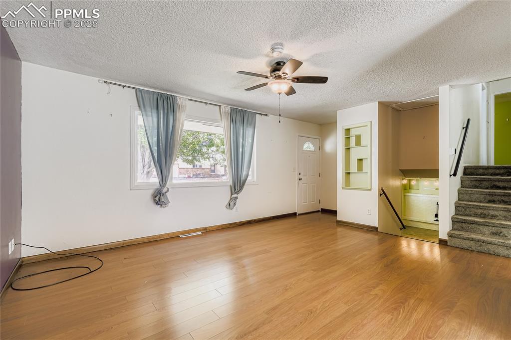 Image 5 of 28: Unfurnished living room with stairway, light wood finished floors, a textur