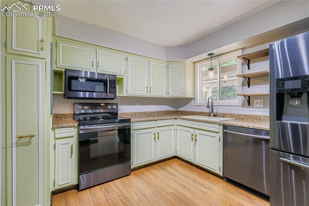 Image 9 of 28: Kitchen featuring stainless steel appliances, open shelves, light wood-styl