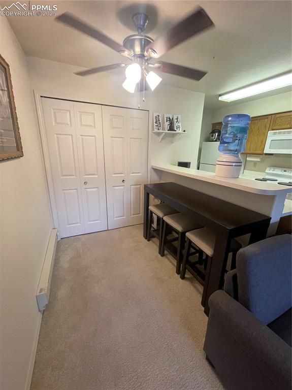 Image 6 of 24: Kitchen featuring ceiling fan, light colored carpet, kitchen peninsula, a k