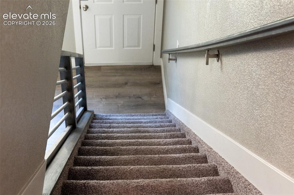 Image 15 of 31: Carpeted staircase featuring a metal handrail and a modern horizontal bar r