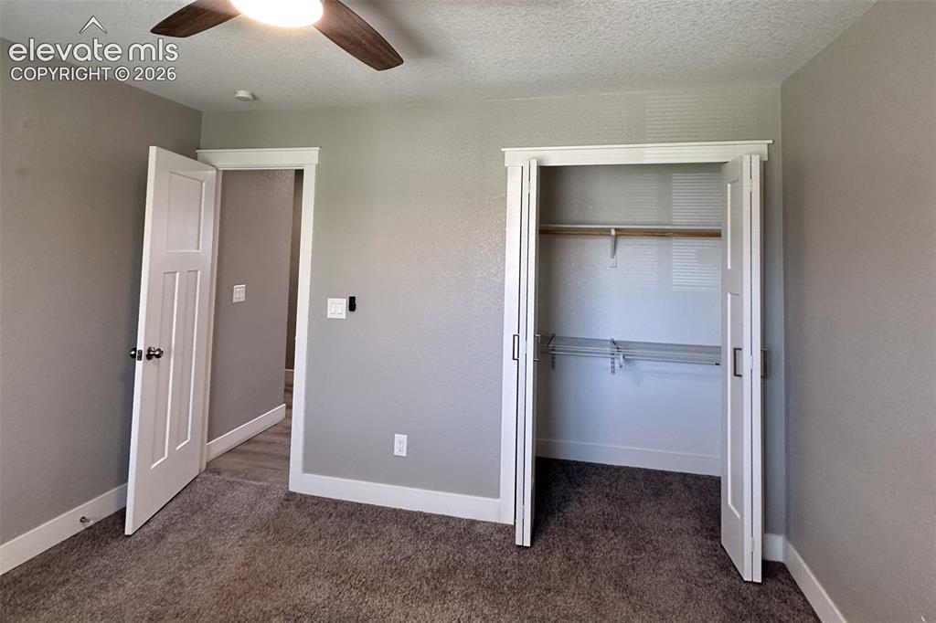 Image 24 of 31: Room featuring textured gray walls, white trim, and brown textured carpetin