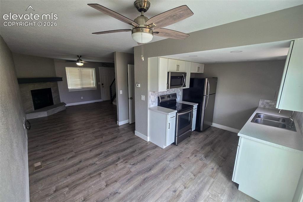 Image 8 of 31: Open-concept living area featuring wood-finish flooring, a stone fireplace,