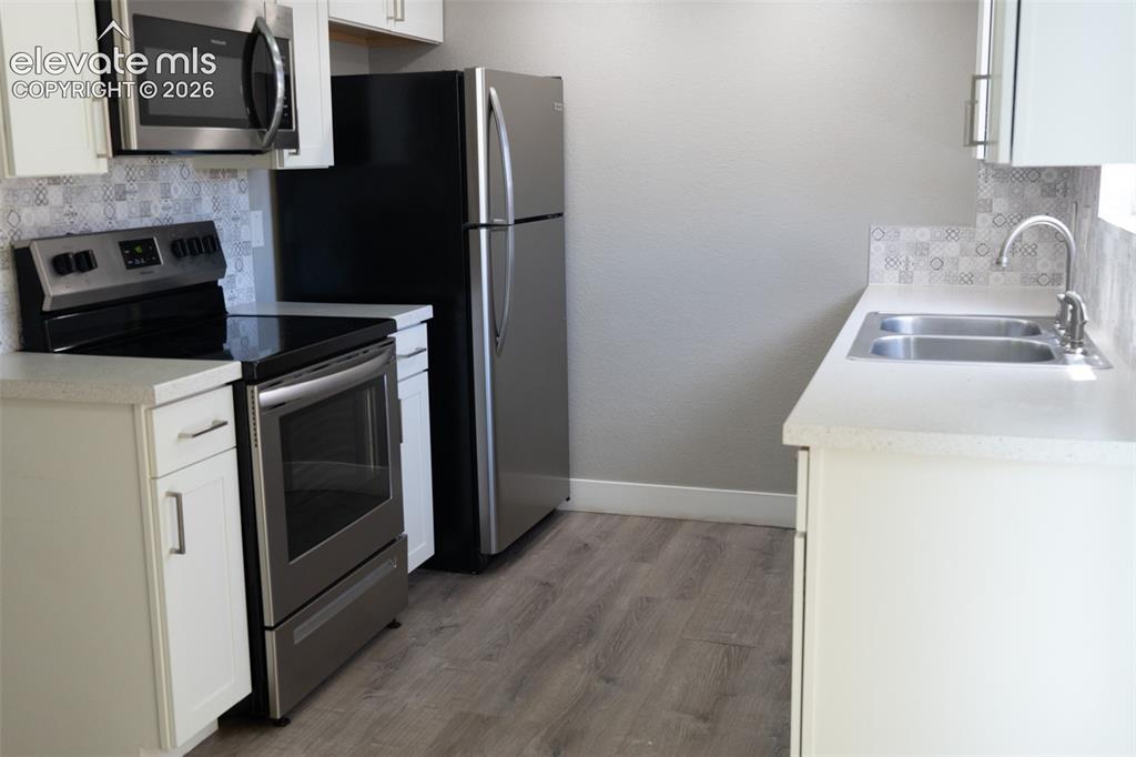 Image 9 of 31: Kitchen featuring wood-finish flooring, white cabinetry, a dual-basin stain