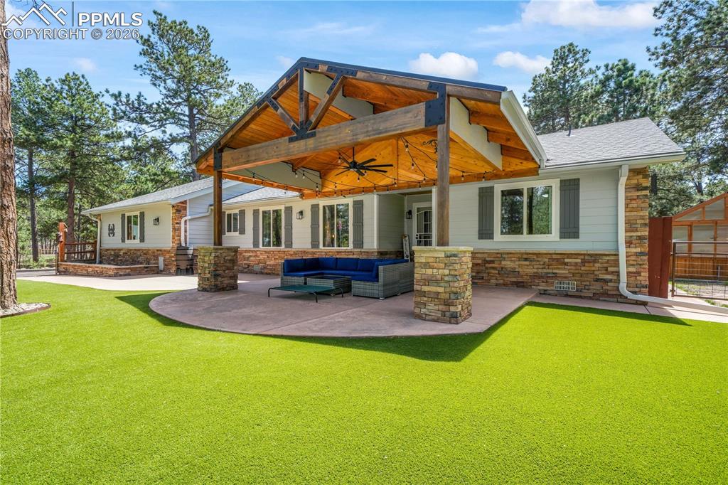 Image 2 of 50: Covered stamped concrete patio at entrance of home with turf and fenced fro