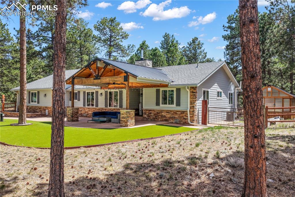Image 7 of 50: Covered stamped concrete patio at entrance of home with turf and fenced fro