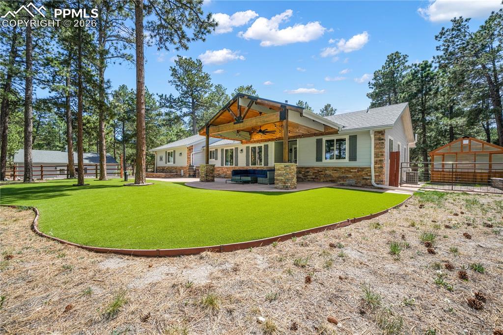 Image 8 of 50: Covered stamped concrete patio at entrance of home with turf and fenced fro