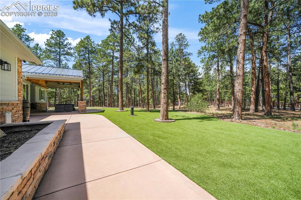 Image 9 of 50: Covered stamped concrete patio at entrance of home with turf and fenced fro