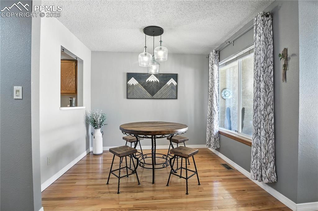 Image 10 of 25: Dining area featuring light wood finished floors, stairway, and a textured 