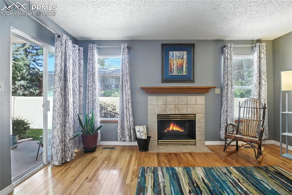 Image 6 of 25: Spacious living room features a cozy gas fireplace and walks out to a priva