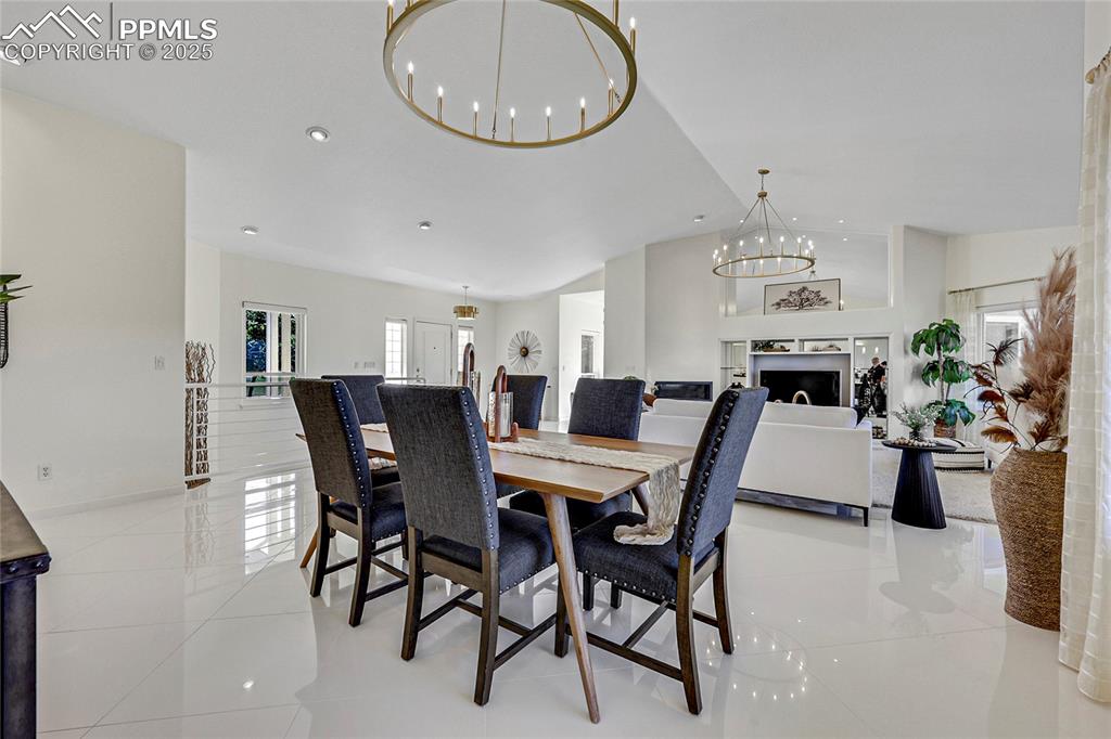 Image 12 of 48: Dining space featuring a chandelier, vaulted ceiling, and light tile patter
