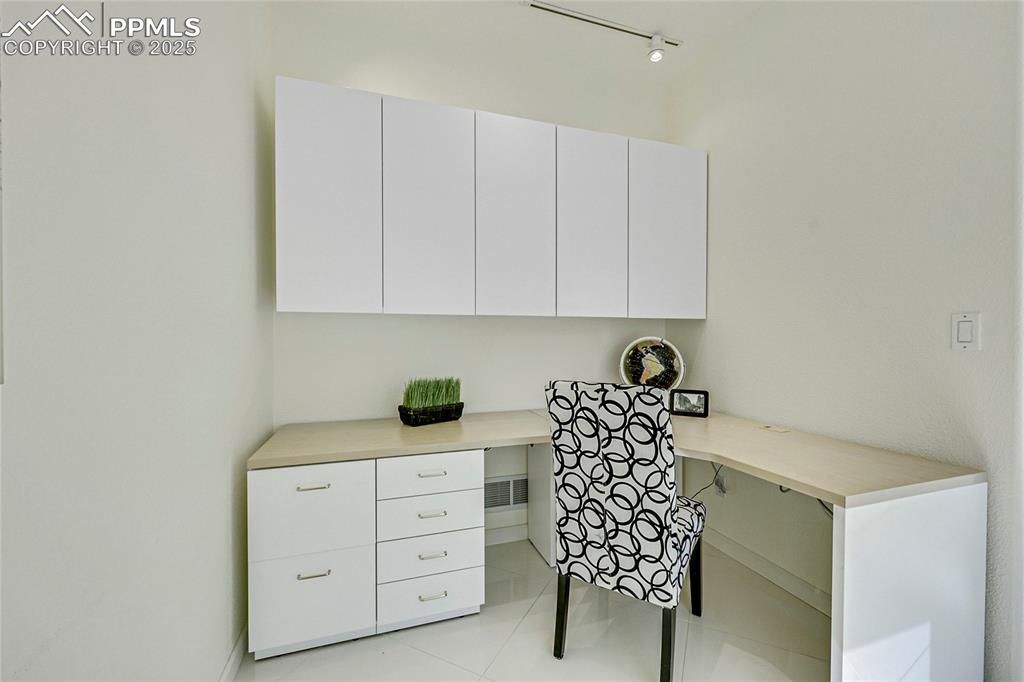 Image 23 of 48: Office with built in desk and light tile patterned floors