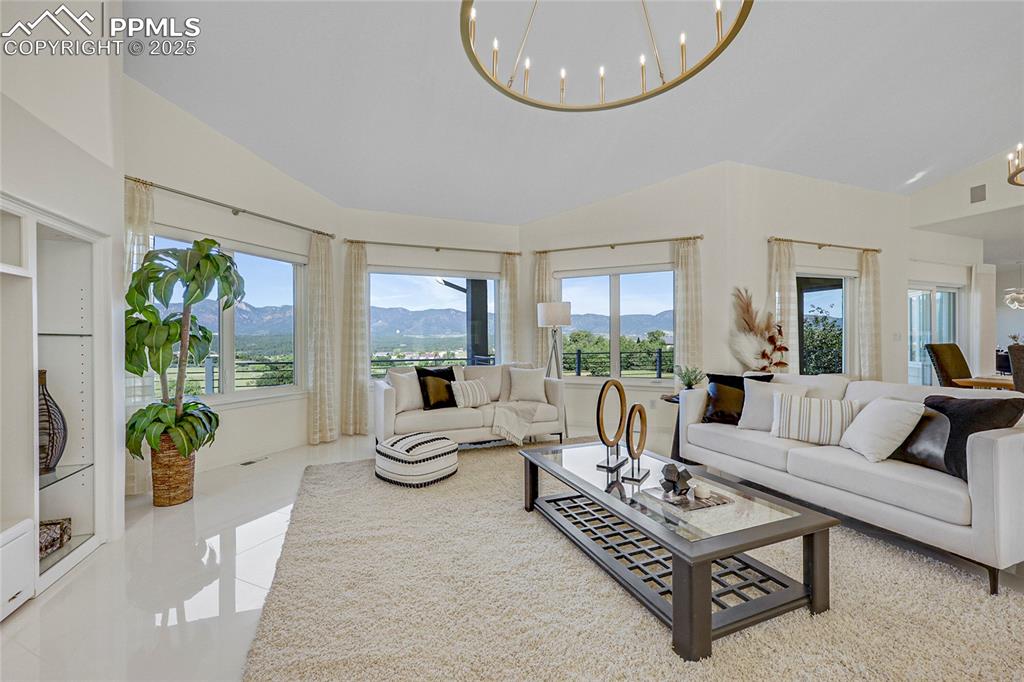 Image 8 of 48: Tiled living room with a mountain view, a chandelier, and high vaulted ceil