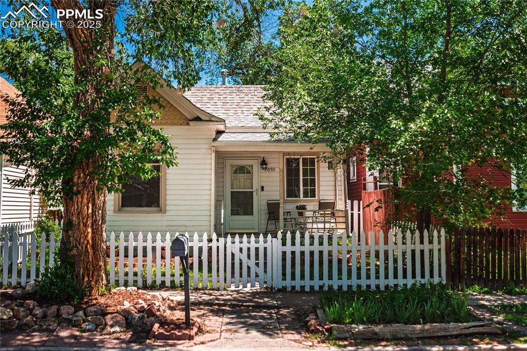 Caption: View of front of property with a shingled roof and a fenced front yard