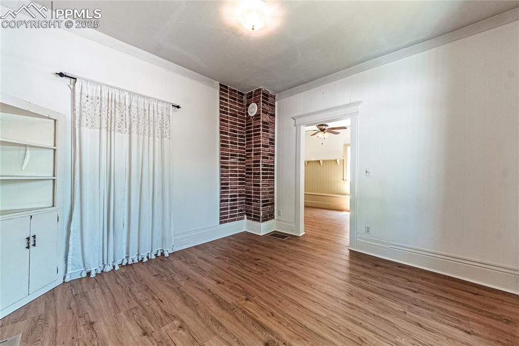 Image 13 of 36: Unfurnished room featuring wood finished floors, ceiling fan, and built in