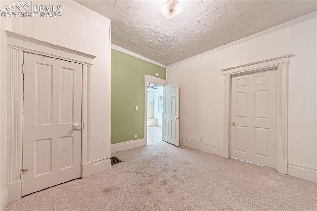 Image 16 of 36: Unfurnished bedroom with carpet floors, ornamental molding, and a textured