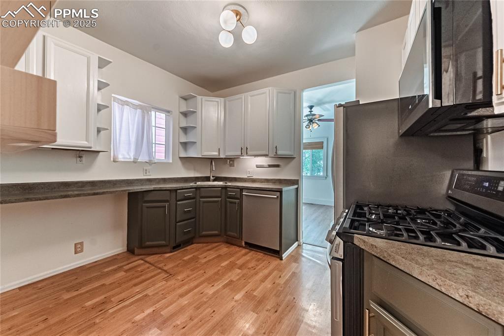 Image 23 of 36: Kitchen with stainless steel appliances, open shelves, light wood-style flo