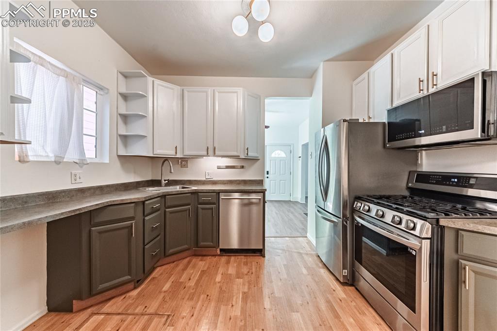 Image 24 of 36: Kitchen with appliances with stainless steel finishes, open shelves, light