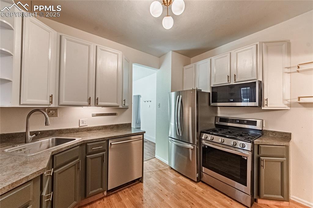 Image 25 of 36: Kitchen with open shelves, stainless steel appliances, light wood-style flo