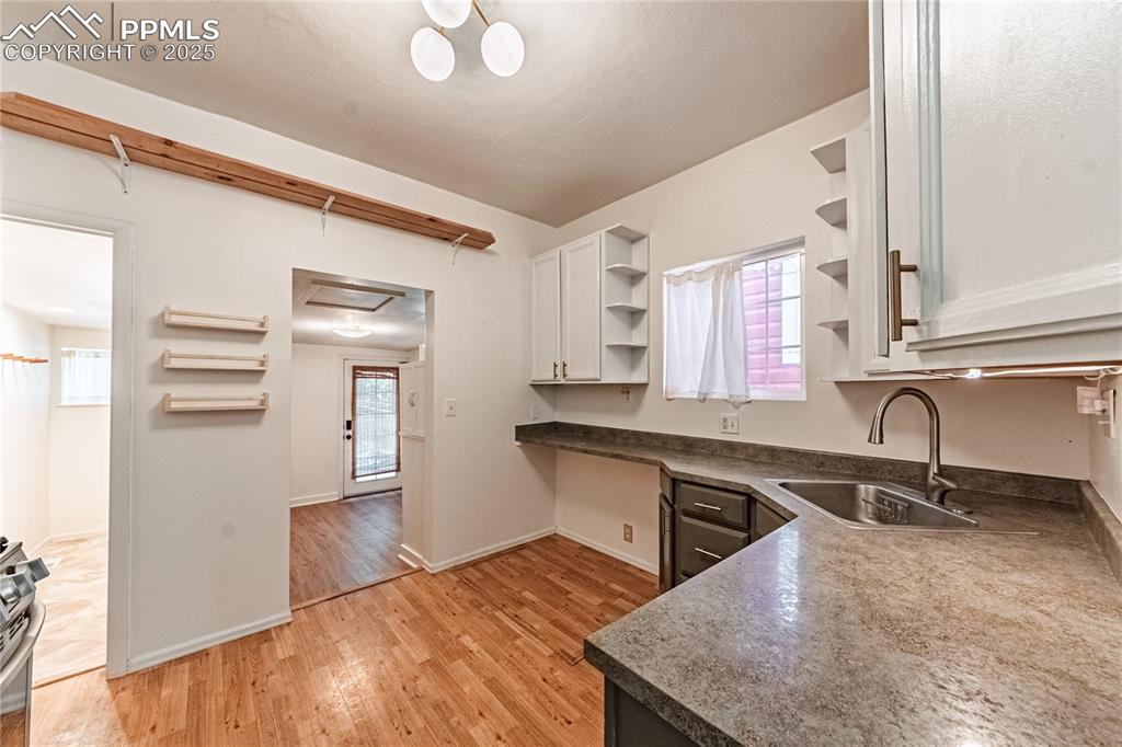 Image 26 of 36: Kitchen featuring open shelves, dark countertops, light wood-style flooring