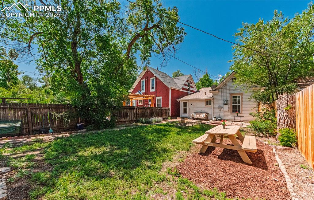 Image 31 of 36: Fenced backyard with a patio area