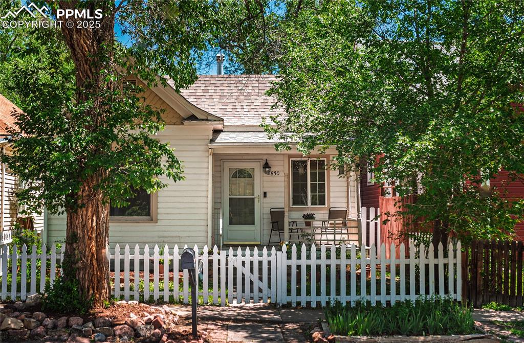 Image 36 of 36: View of front of house with a shingled roof and a fenced front yard