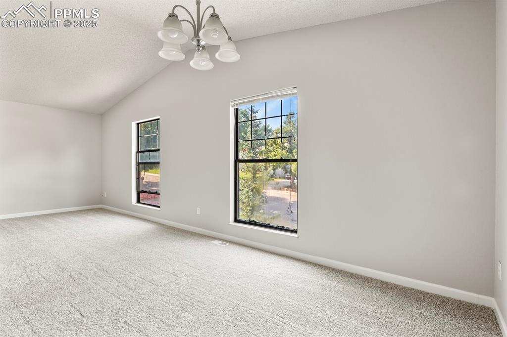 Image 12 of 39: Empty room with carpet floors, lofted ceiling, a chandelier, healthy amount