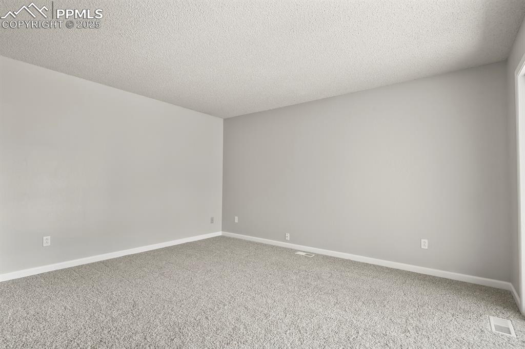 Image 16 of 39: Carpeted spare room featuring a textured ceiling and baseboards