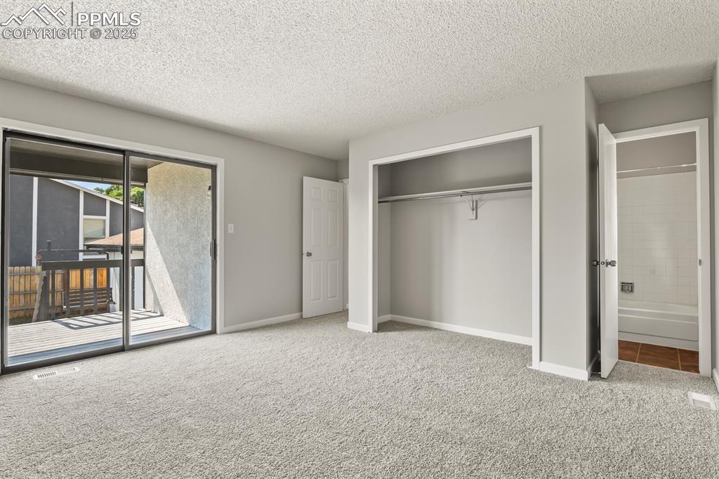 Image 17 of 39: Unfurnished bedroom featuring access to outside, carpet, a textured ceiling