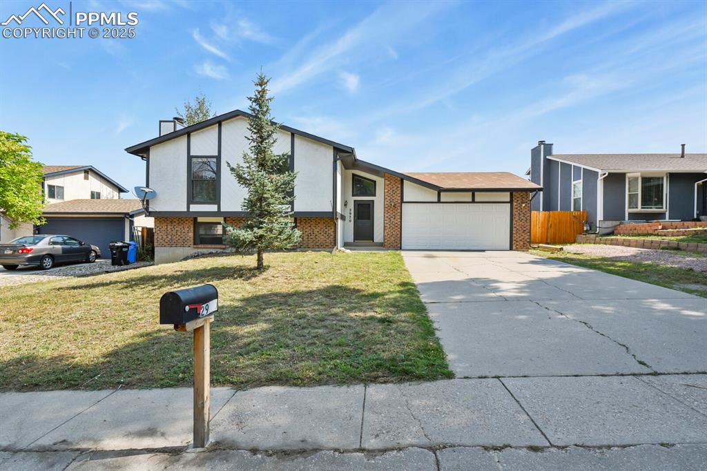 Image 2 of 39: View of front of home with brick siding, an attached garage, concrete drive