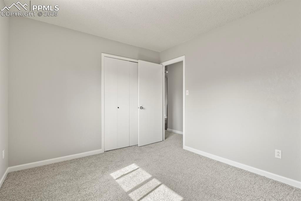 Image 21 of 39: Unfurnished bedroom featuring carpet floors, a textured ceiling, and a clos