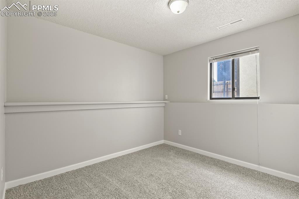 Image 26 of 39: Carpeted spare room with a textured ceiling and baseboards