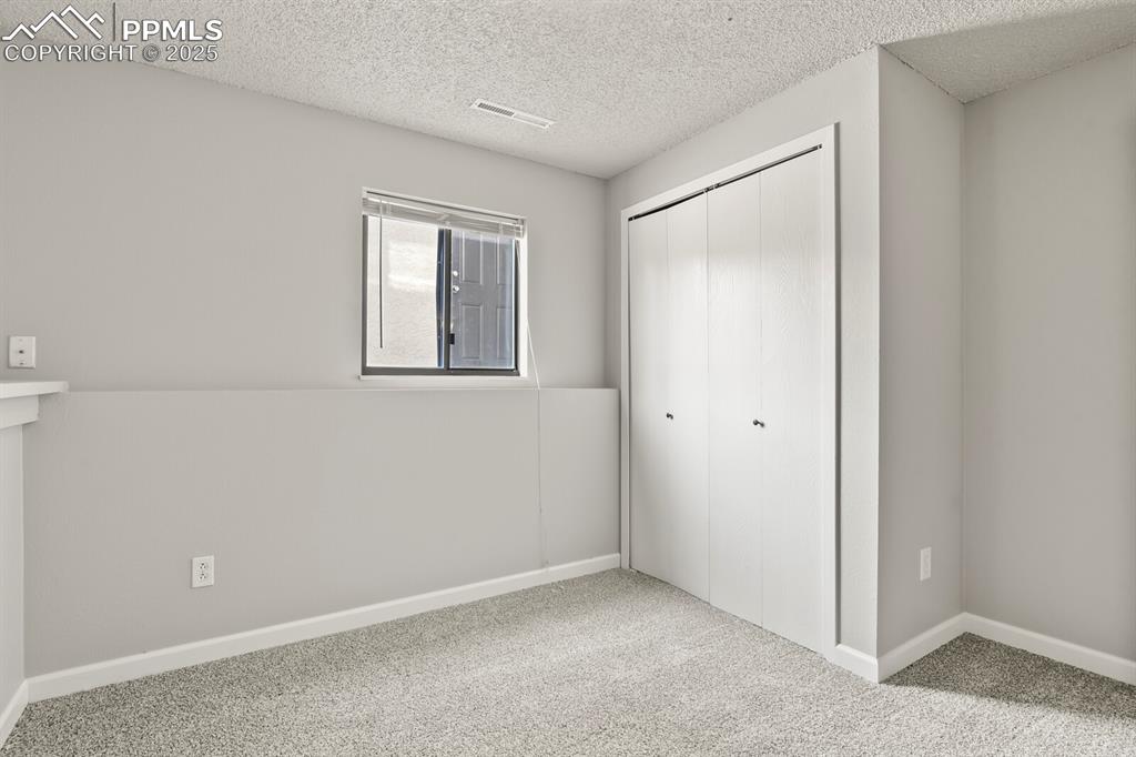 Image 27 of 39: Unfurnished bedroom with a textured ceiling, carpet floors, and a closet