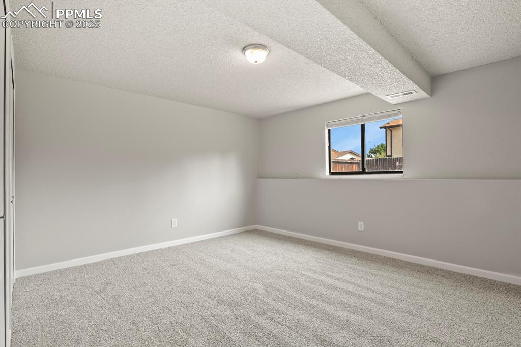 Image 29 of 39: Carpeted empty room featuring a textured ceiling and baseboards