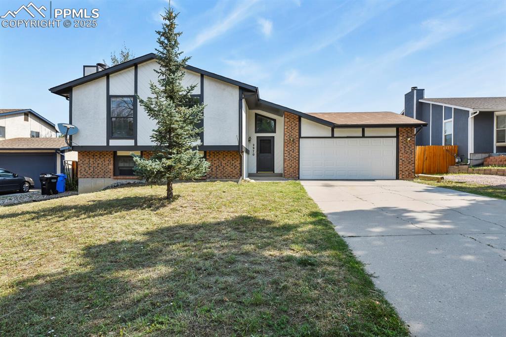 Image 3 of 39: View of front of home with brick siding, concrete driveway, an attached gar