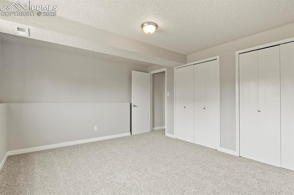 Image 30 of 39: Unfurnished bedroom with multiple closets, carpet, and a textured ceiling