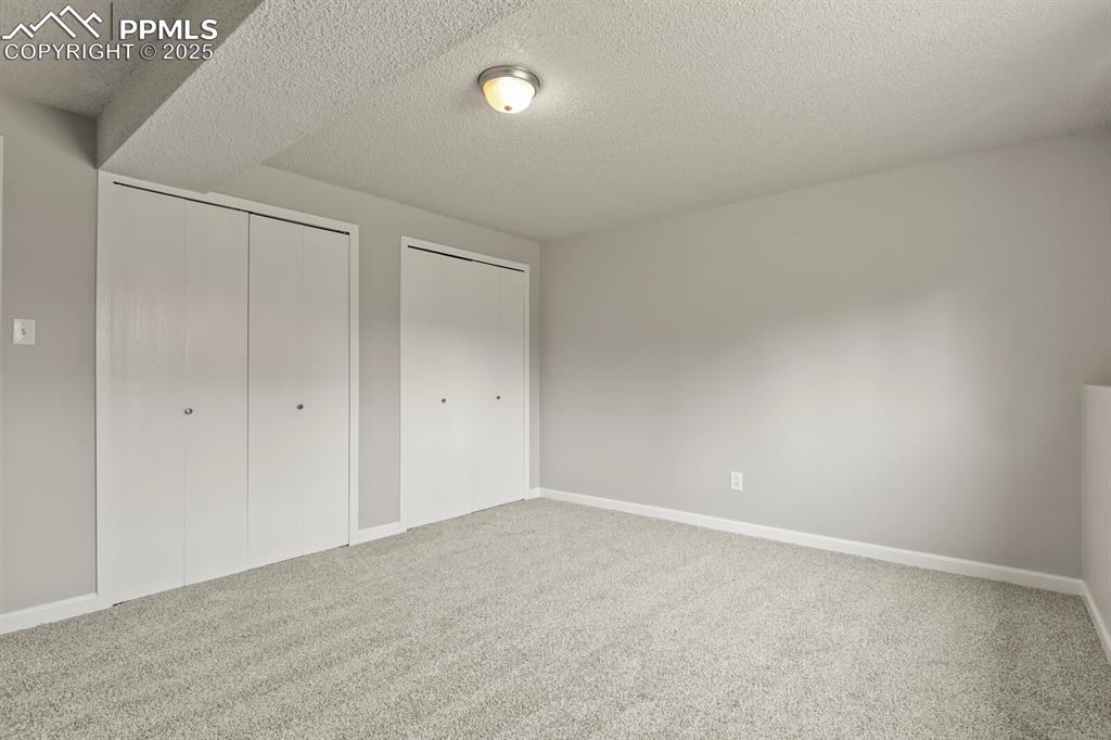 Image 31 of 39: Unfurnished bedroom featuring multiple closets, a textured ceiling, and car