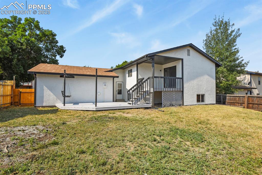 Image 36 of 39: Rear view of house featuring a fenced backyard, stucco siding, and a deck