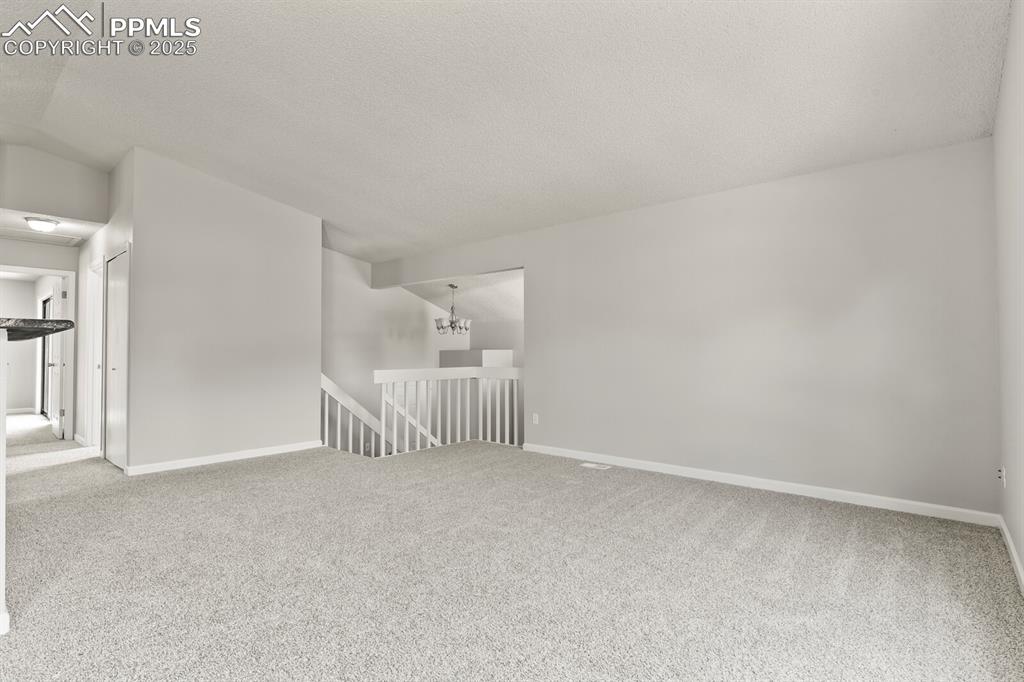 Image 9 of 39: Carpeted empty room featuring a textured ceiling and a chandelier