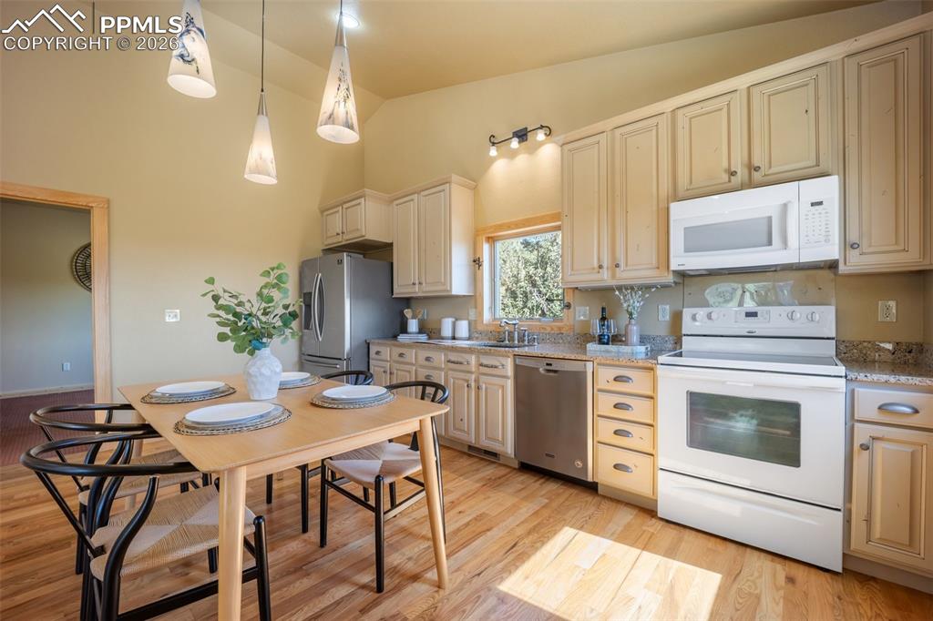 Image 10 of 50: Kitchen with stainless steel appliances, lofted ceiling, light stone counte