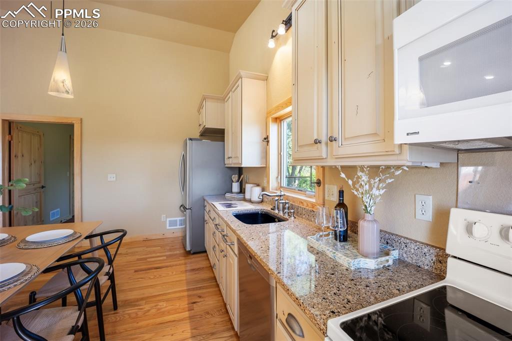 Image 11 of 50: Kitchen with stainless steel appliances, light stone countertops, light woo