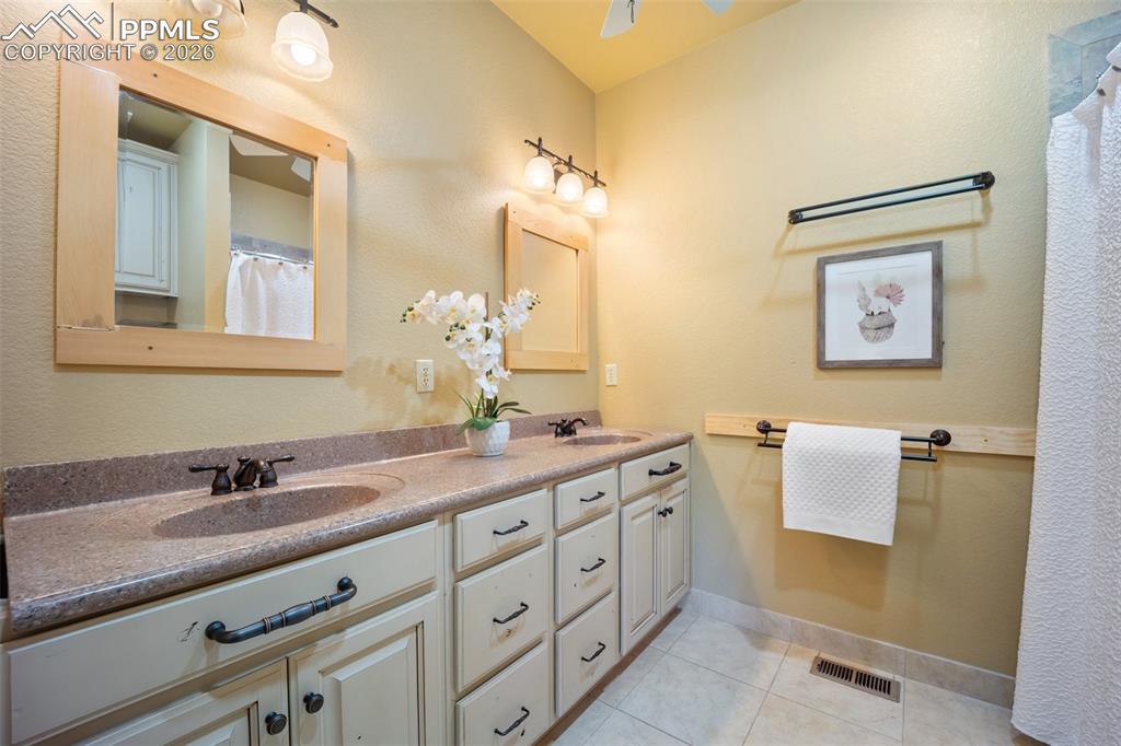 Image 19 of 50: Bathroom with double vanity, a shower with curtain, light tile patterned fl