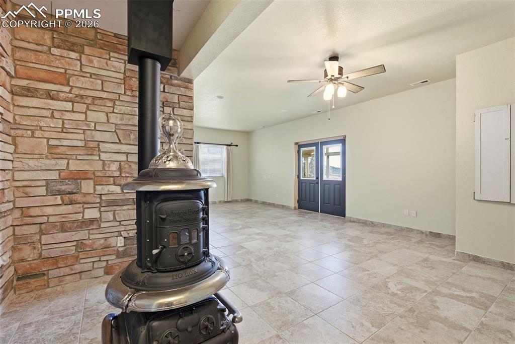 Image 35 of 50: Unfurnished living room featuring a wood stove and a ceiling fan