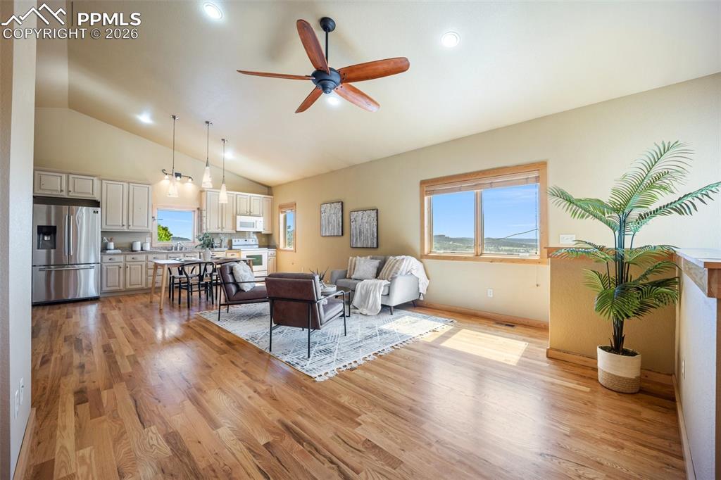 Image 5 of 50: Living area with ceiling fan, light wood-style flooring, vaulted ceiling, a