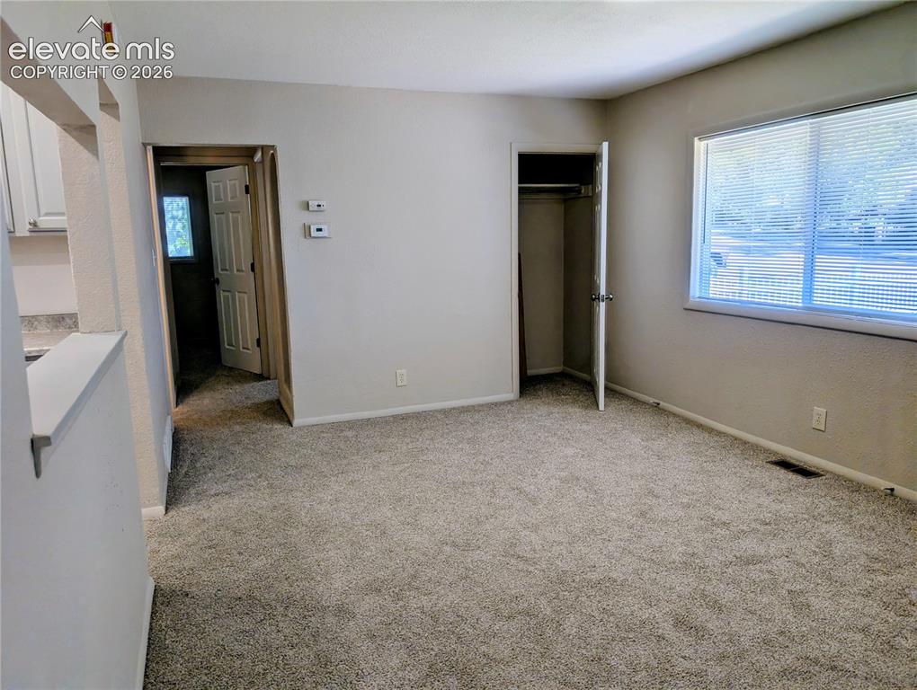 Image 3 of 39: Living room looking towards kitchen, hallway, & coat closet